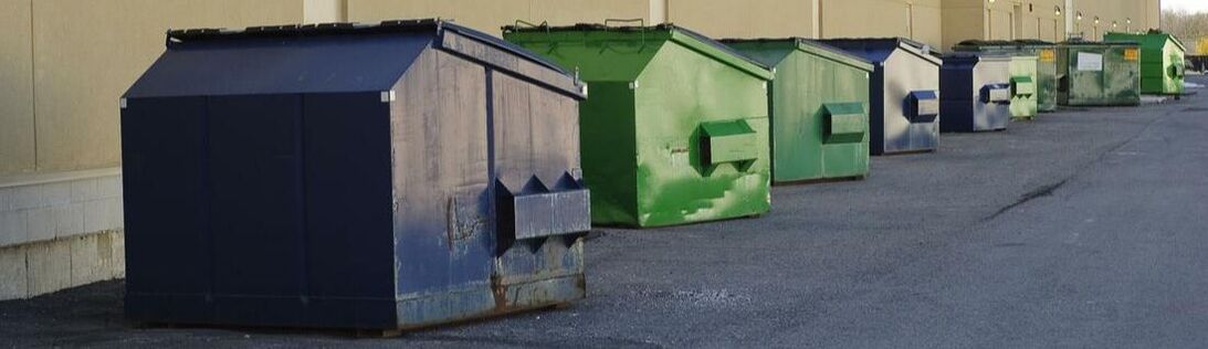 Several commercial dumpsters lined up outside a building